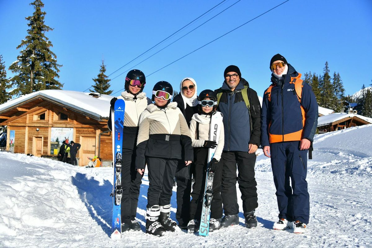 Instructor with a family of five in front of a wooden chalet