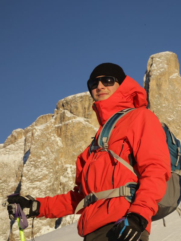 Portrait of Emanuele in a red jacket in front of rocky peaks