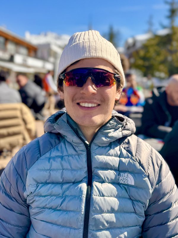 Portrait of Paolo smiling on a sunny terrace in the resort, wearing a beanie and sunglasses