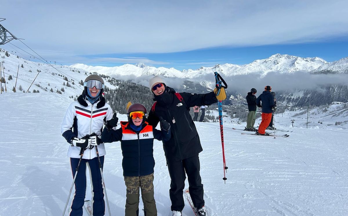 Instructor with a mother and son on a sunny slope above the valley