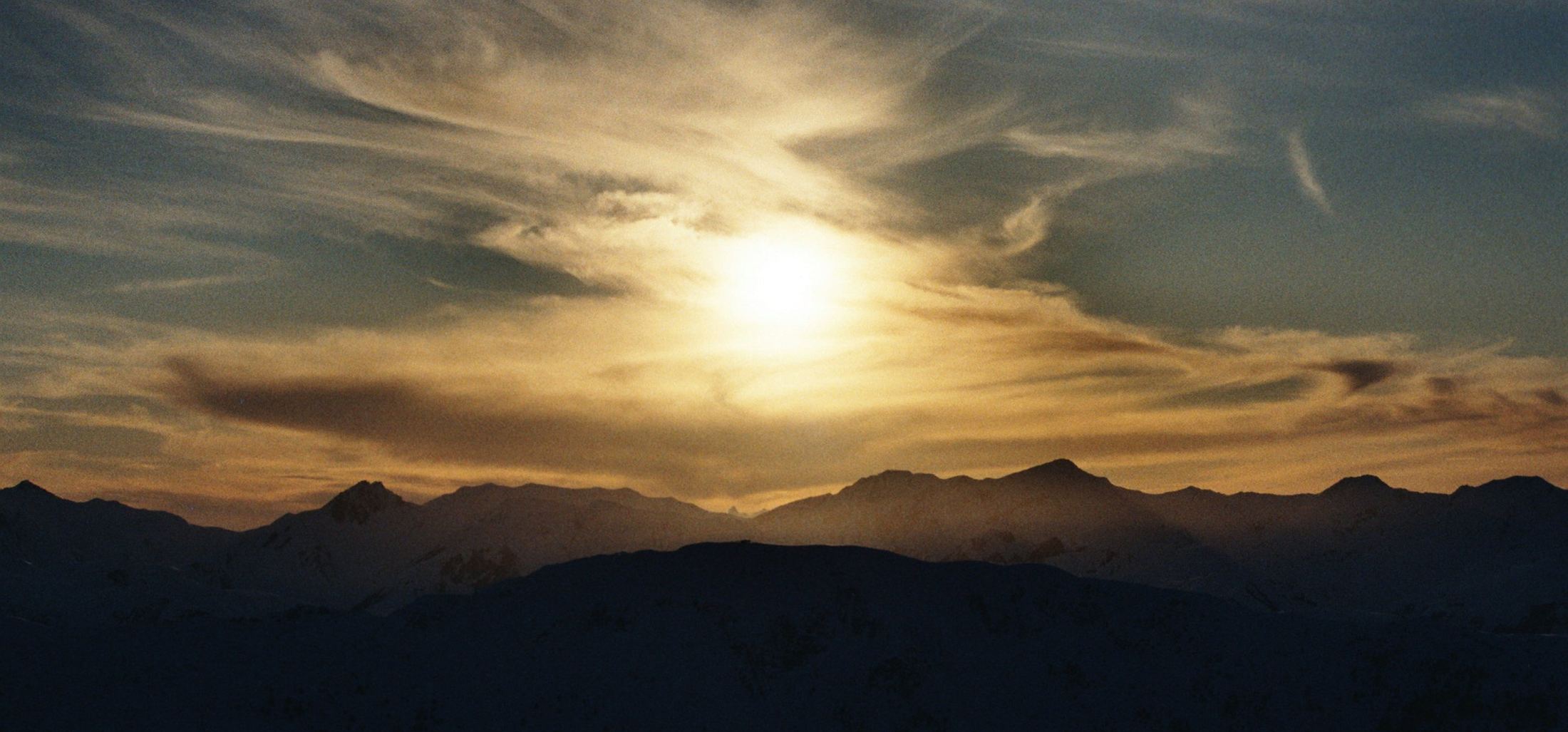 Atardecer sobre una cresta de montaña con el cielo dorado
